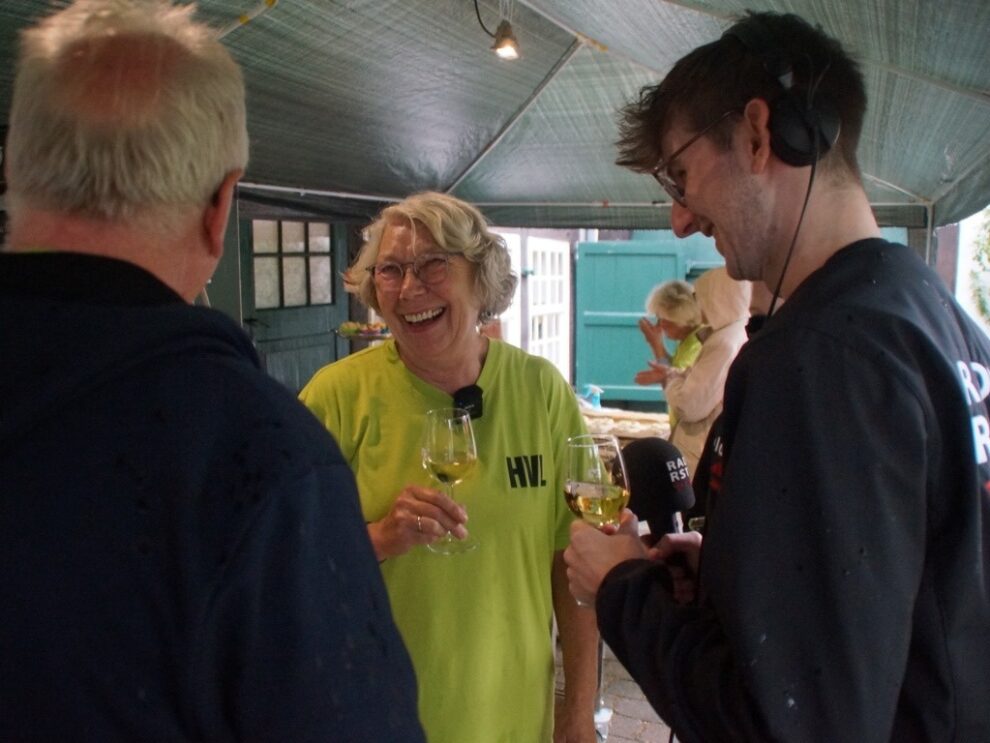 Ein Radioreporter unterhält sich am Gebäckstand mit einer lachenden Helferin.