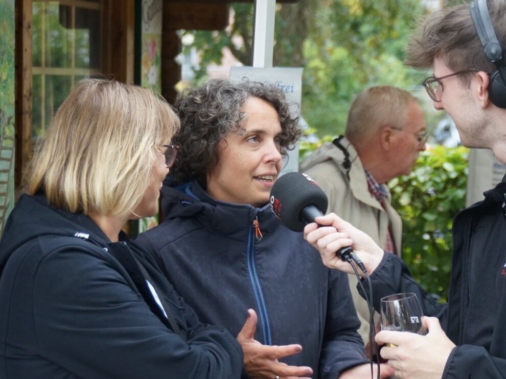 Eine Frau spricht bei einem Interview auf dem Weinfest in das Mikrofon eines Radioreporters.