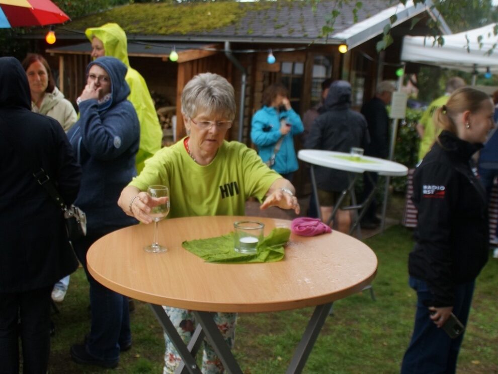 Eine Helferin wischt bei regnerischem Wetter einen Stehtisch auf dem Weinfest ab.