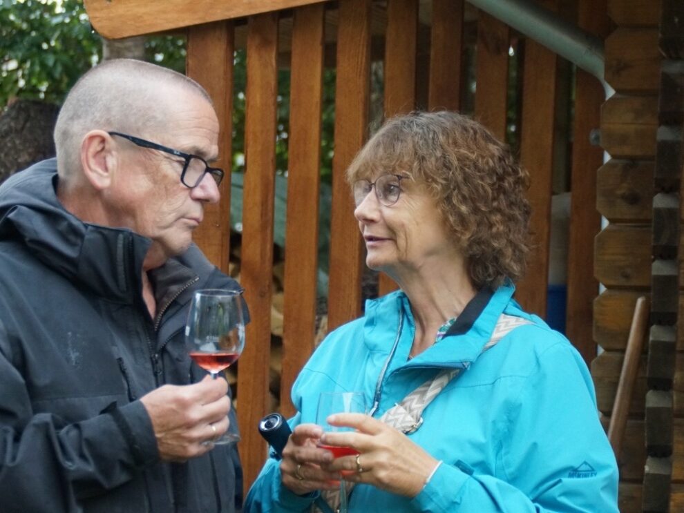 Ein Mann und eine Frau sprechen miteinander und halten Gläser mit Roséwein.