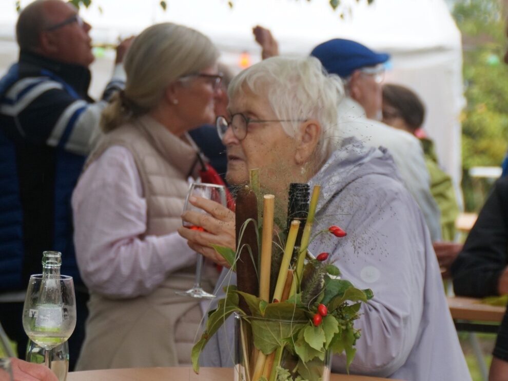 Eine Frau hält ein Glas Roséwein hinter einem herbstlich geschmückten Tisch.