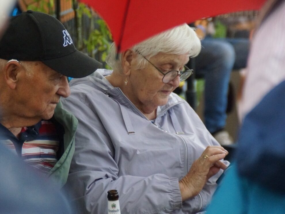 Ein Mann und eine Frau sitzen bei Regen nebeneinander im Festzelt.